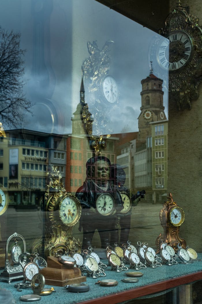 A vintage clock display reflecting city architecture in a store window.