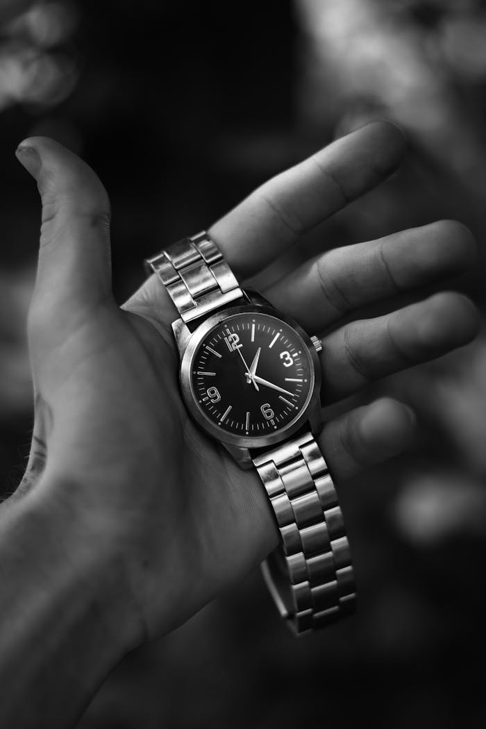 Crafting Captivating Headlines: Your awesome post title goes here A detailed black and white close-up of a hand holding a classic wristwatch with a metal band.