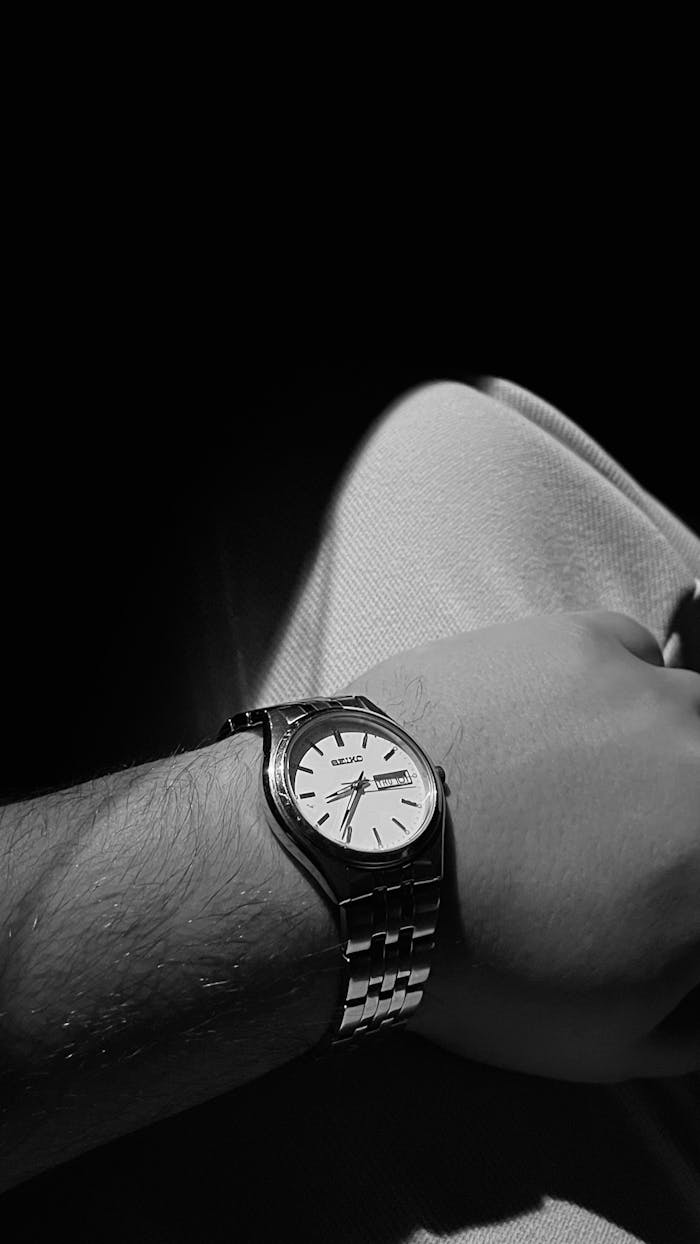 Black and white close-up of a Seiko wristwatch worn on a human arm, showcasing time and style.