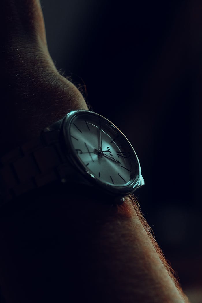 A timeless analog wristwatch on a wrist with a dark, moody background.